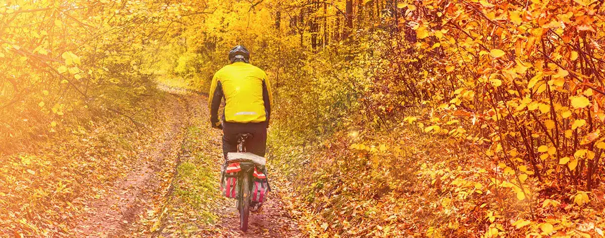 Fall Biking Near Kennebunk, Maine Cyclist in a yellow jacket riding a wooded trail lined with golden fall foliage